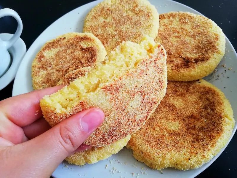 Round Moroccan harsha bread made from semolina. The inside is yellow and the outside is cooked on a pan with a light brown color. 