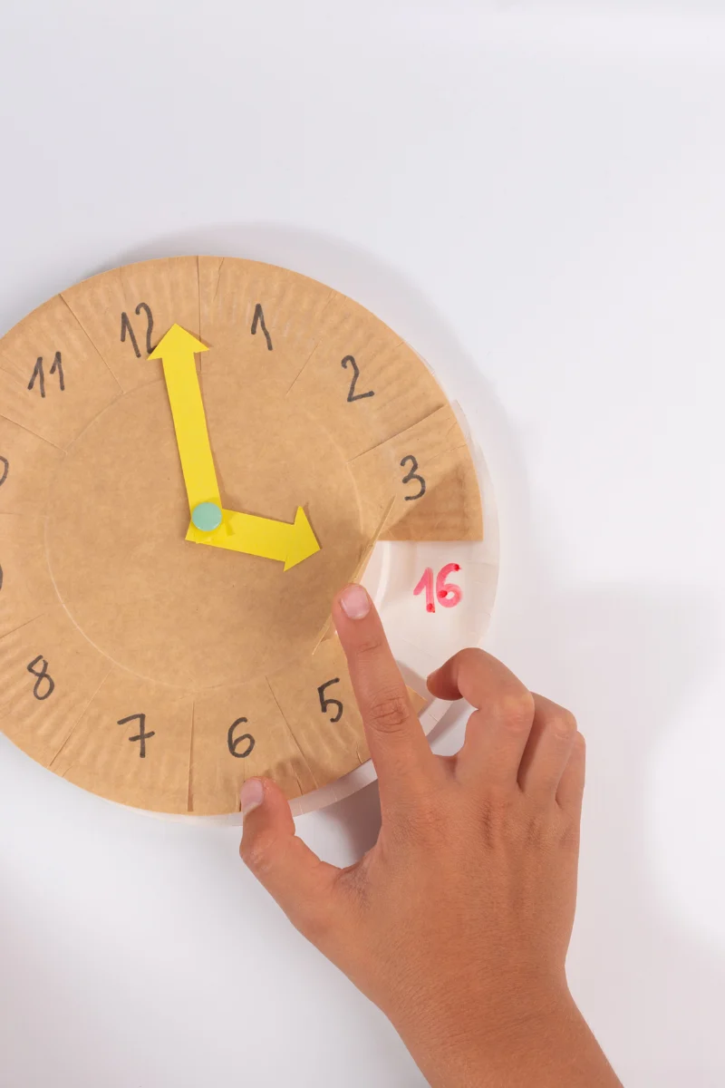 someone holding a paper clock for telling time in Darija