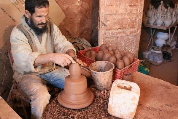Moroccan Man sits at a pottery wheel making traditional Moroccan pottery