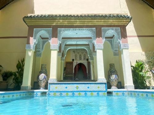 Arched doors with pillars in background, plunge pool in foreground. Courtyard in a Fez Riad. 