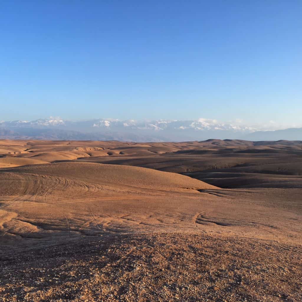Moroccan stone desert with snowcapped Atlas Mountains and blue sky