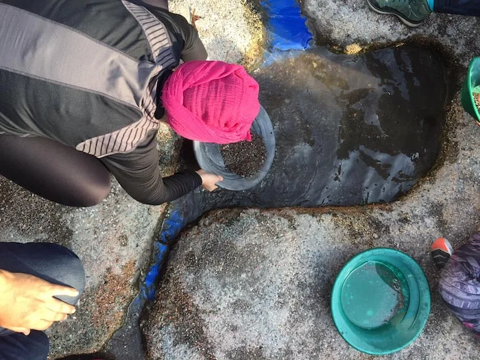 Woman with a pan in her hand and running water looking for gold.