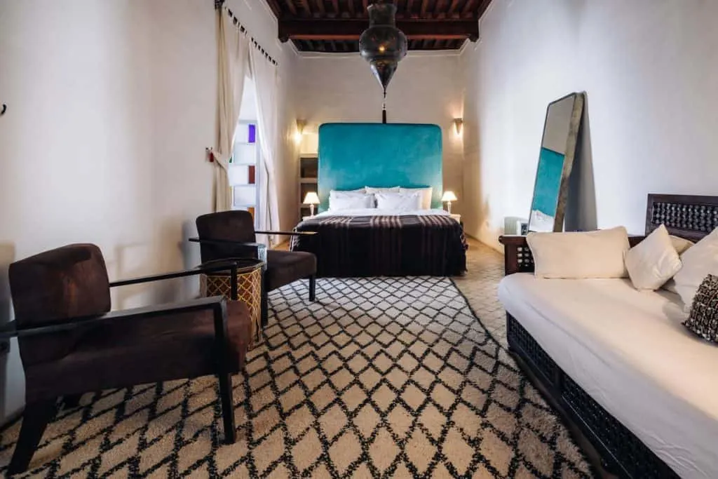 Open riad room with black and white floor and full size bed in restored Fez riad