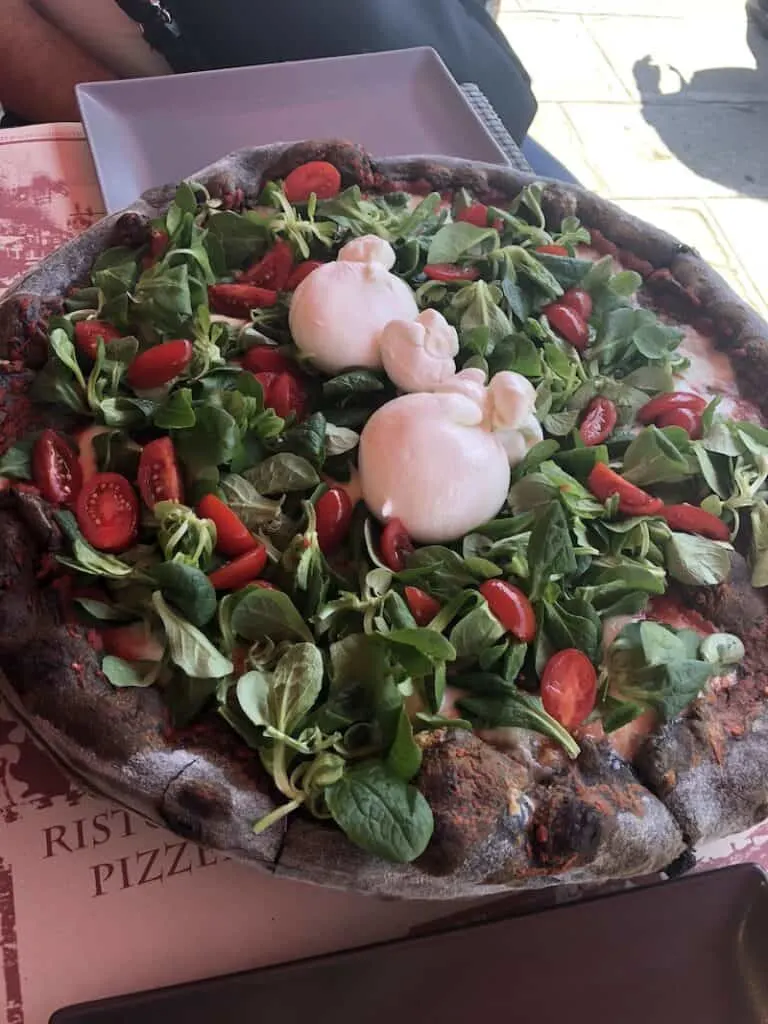 Vegetarian pizza with a black crust at a restaurant in Burano Italy.