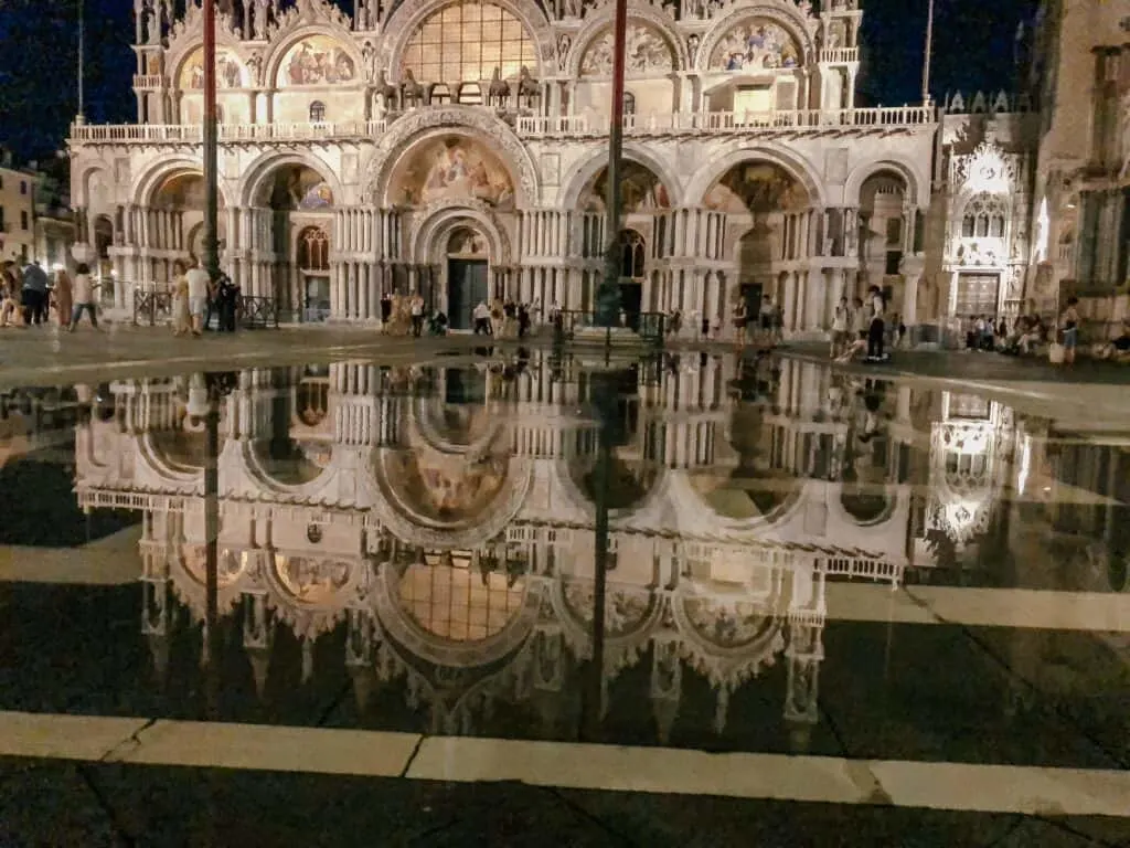 St. Mark\'s Cathedral at night is reflected in the water that has risen in the square from the high tide in Venice.