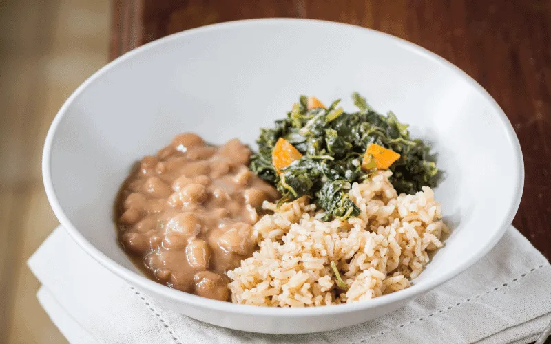 White bowl with cooked beans, white rice and green spinach