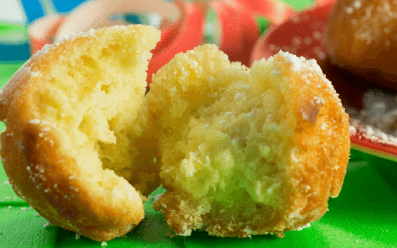Fried round doughnut that is cut in half on a green table.