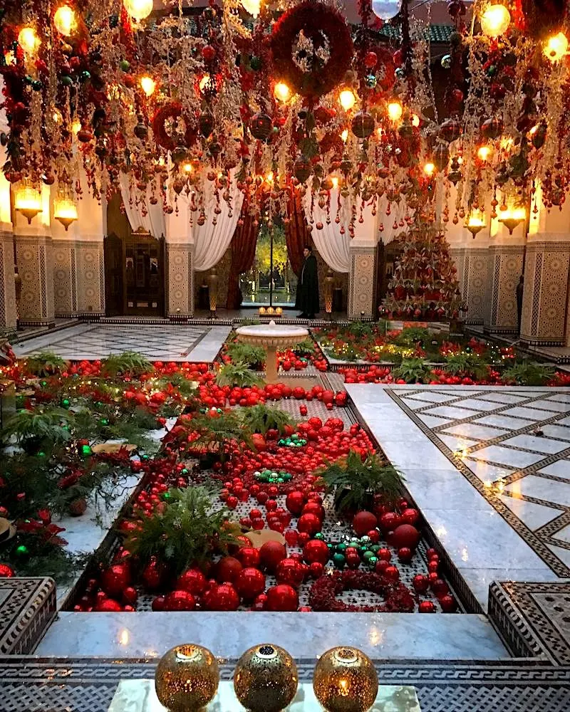 Red Christmas decorations in a Moroccan courtyard with a central pool. 