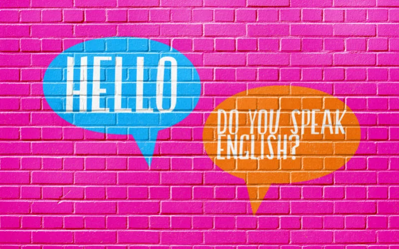 A pink wall has two word bubbles saying hello and do you speak English