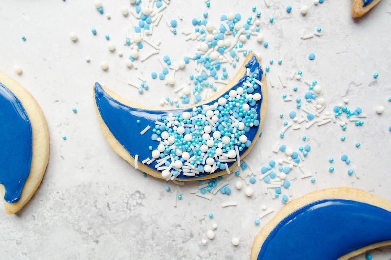 Blue frosted crescent cookie with sprinkles on a table