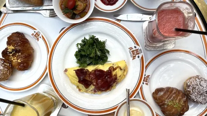 Multiple White plates with breakfast items crowd a table