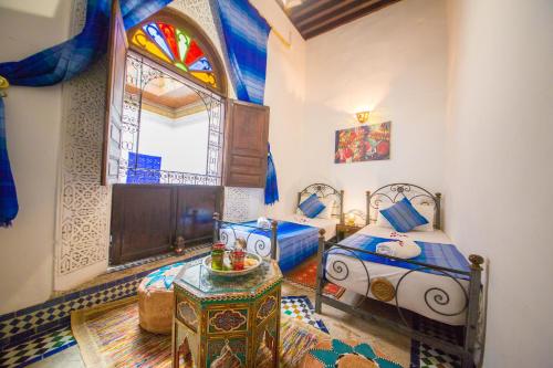 Room with two twin beds and white and blue furnishings in Fez