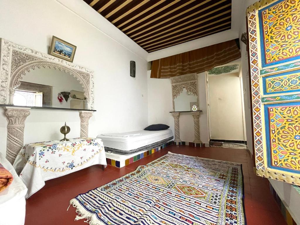 A large simple room with a colored rug on the floor and a single bed near the wall.