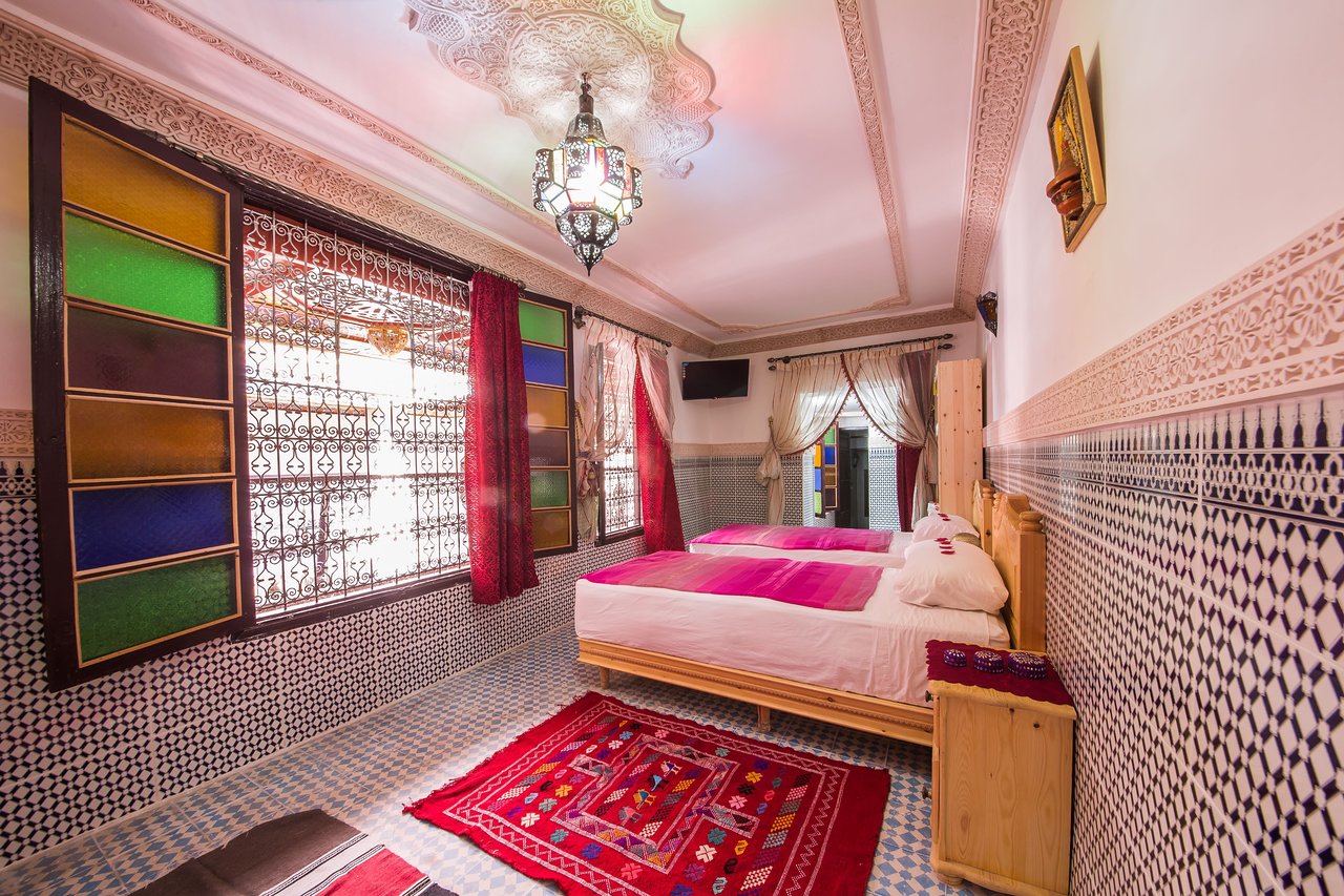 A narrow room with large intricate gated window in a Fez Morocco riad