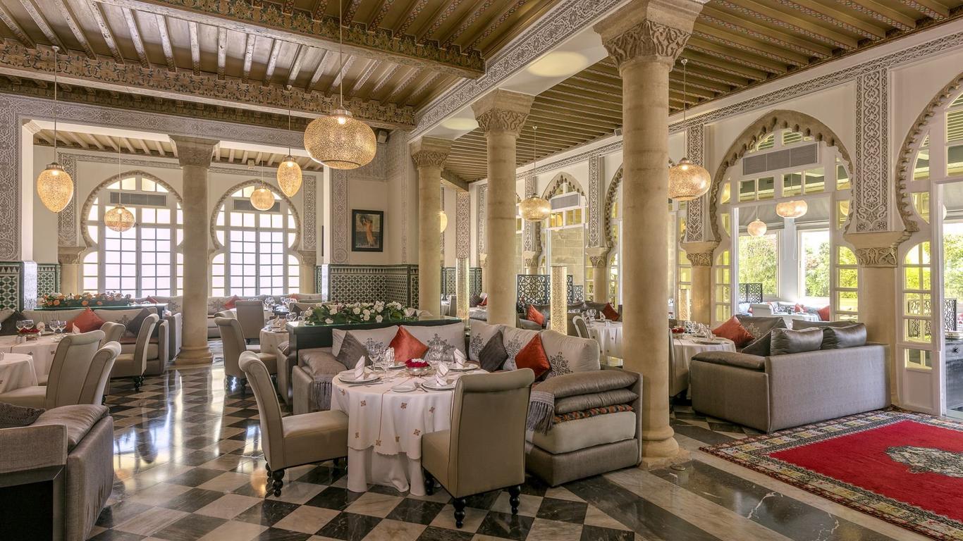 Arched windows and Moroccan style pillars in a dining room with hanging lanterns and dining tables.