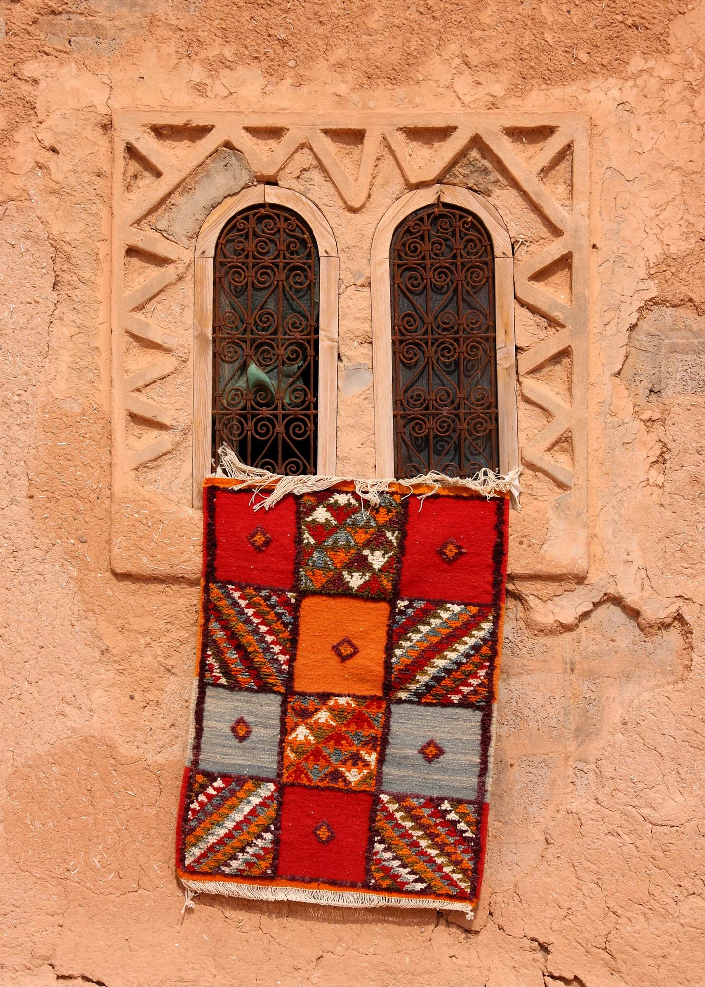 Small red Moroccan rug on a brown wall