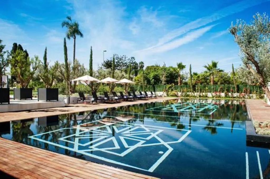 Large bowl with geometric design in the middle. Lounge chairs around the pool and palm trees in background