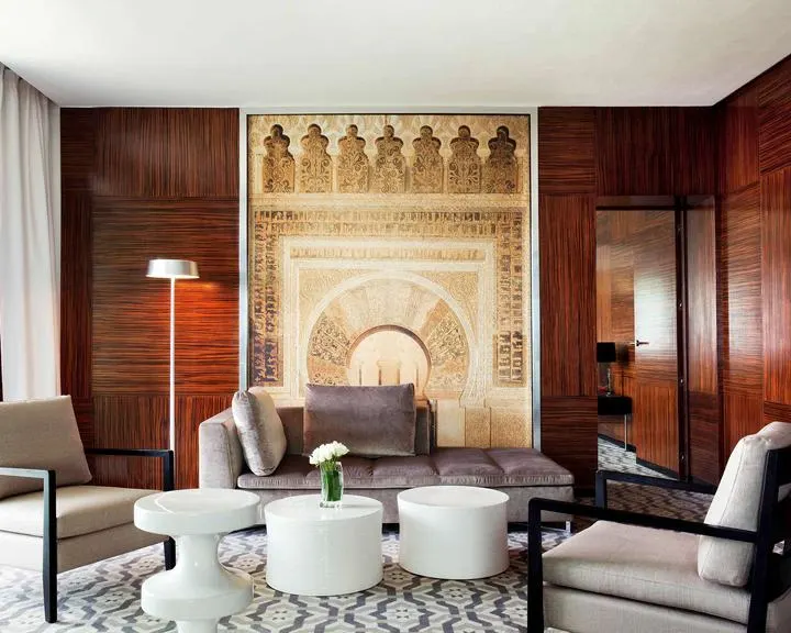 Sitting area with wooden chairs and white ottomans around a Moroccan designed fireplace in Rabat hotel