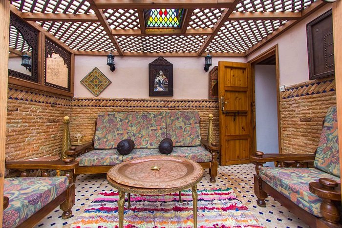 exterior sitting area with 3 couches around a round table and a lattice roof in Fez