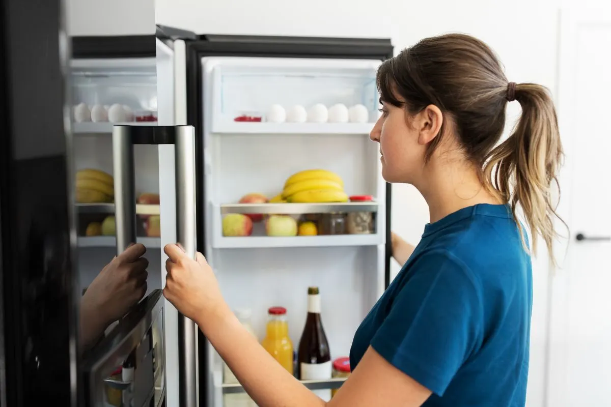 A woman opening the fridge to look for ingredients in making soup