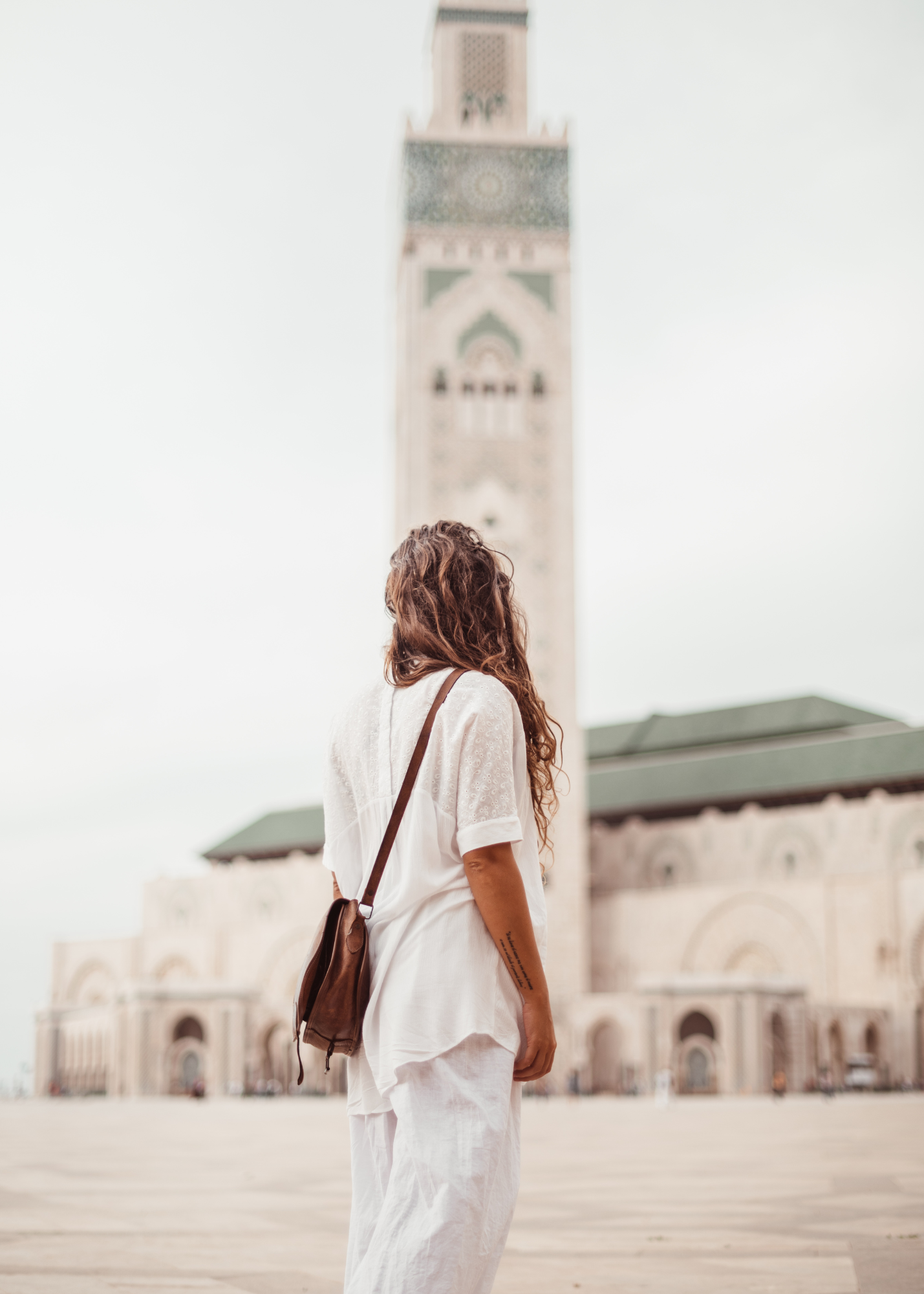 A woman is walking in front of the Hassan II mosque in Casablanca