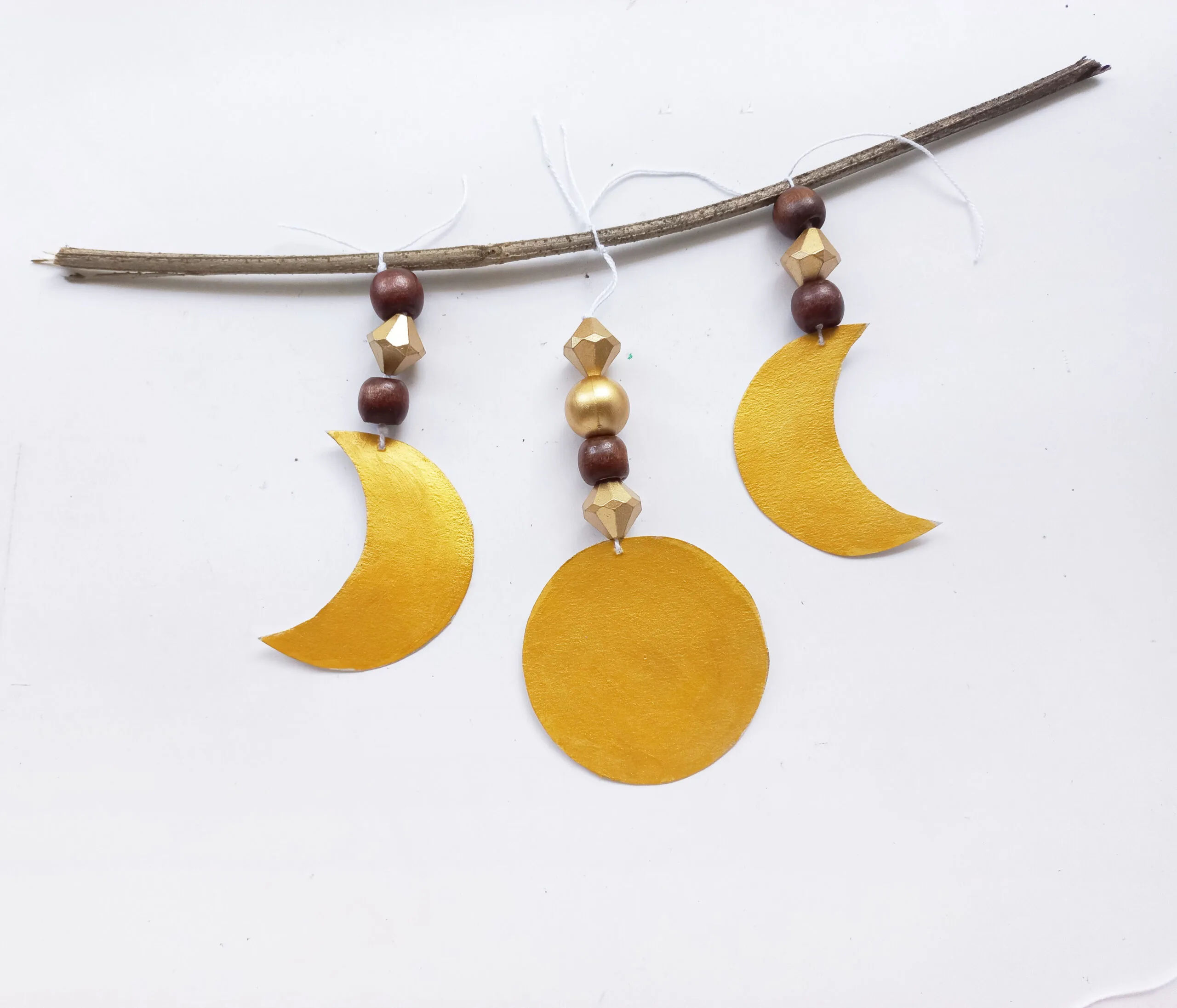 three moon cut out tied to a twig