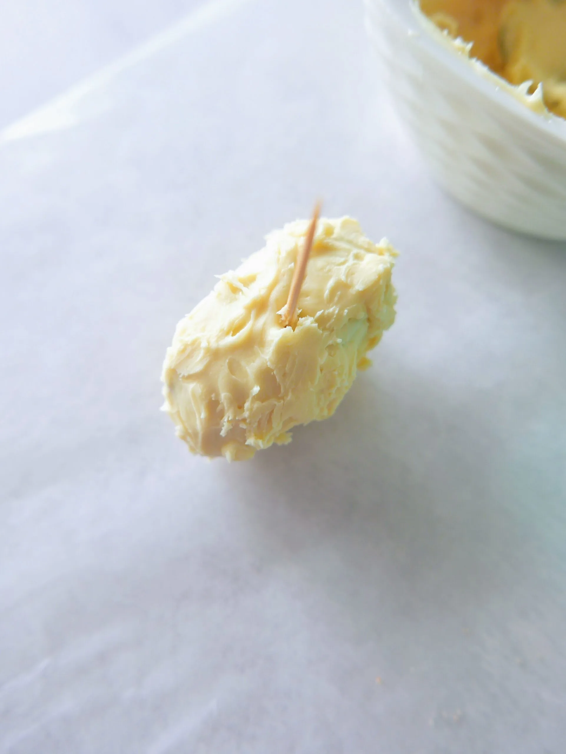 white chocolate stuffed dates with toothpick on a parchment paper