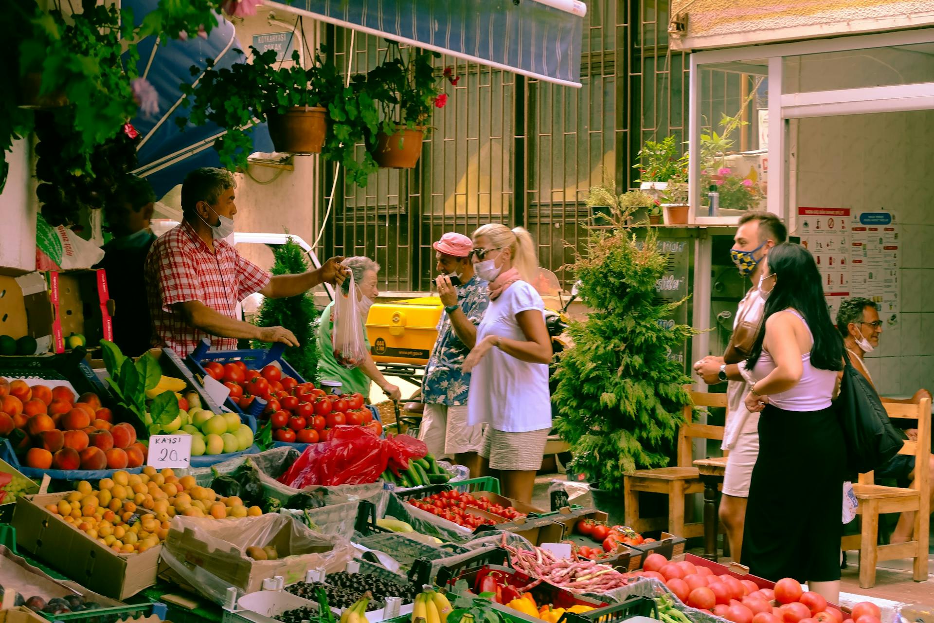 People Walking and Talking in Front of a Vegetable Stand