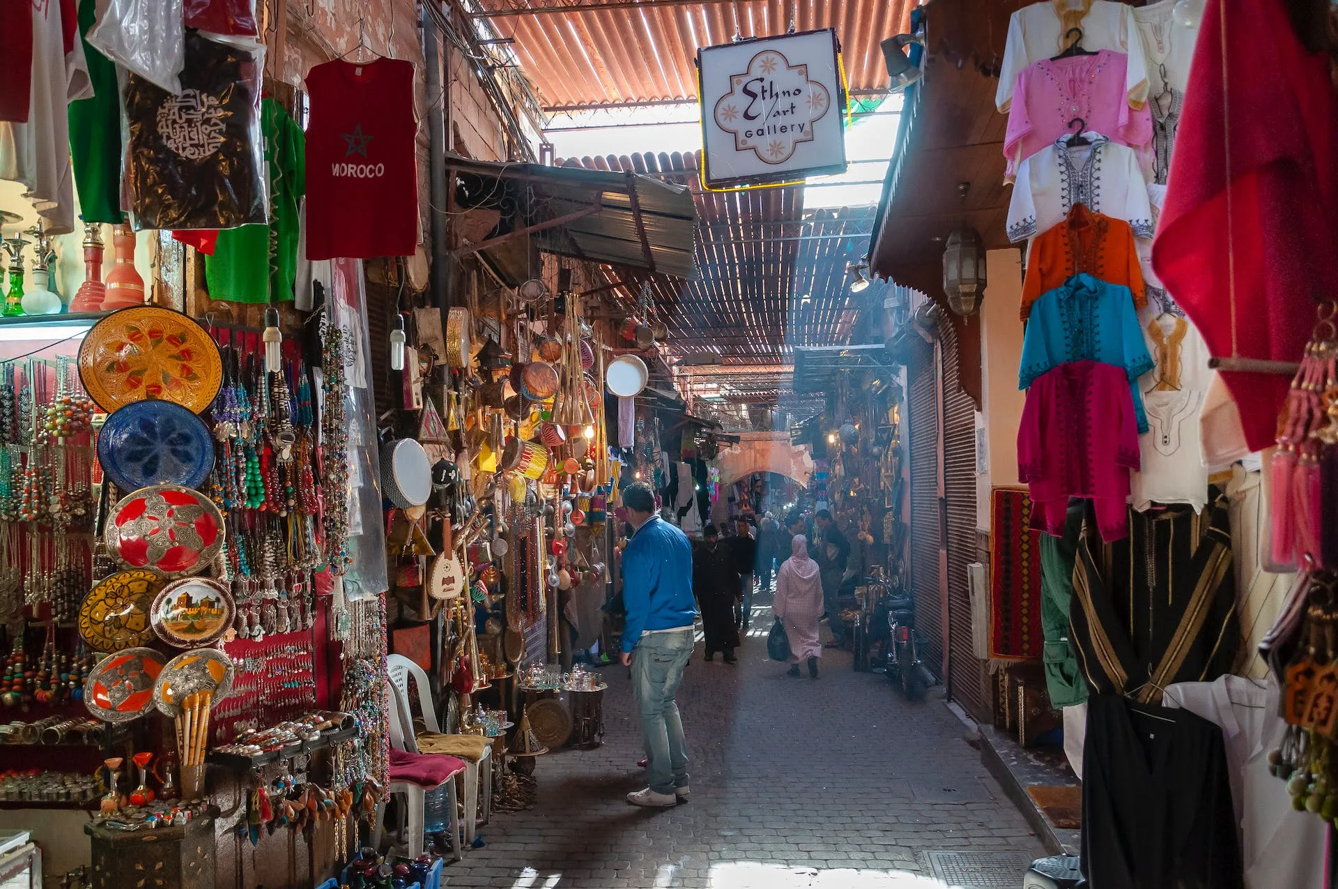 people walking in a local market in Morocco with assorted goods
