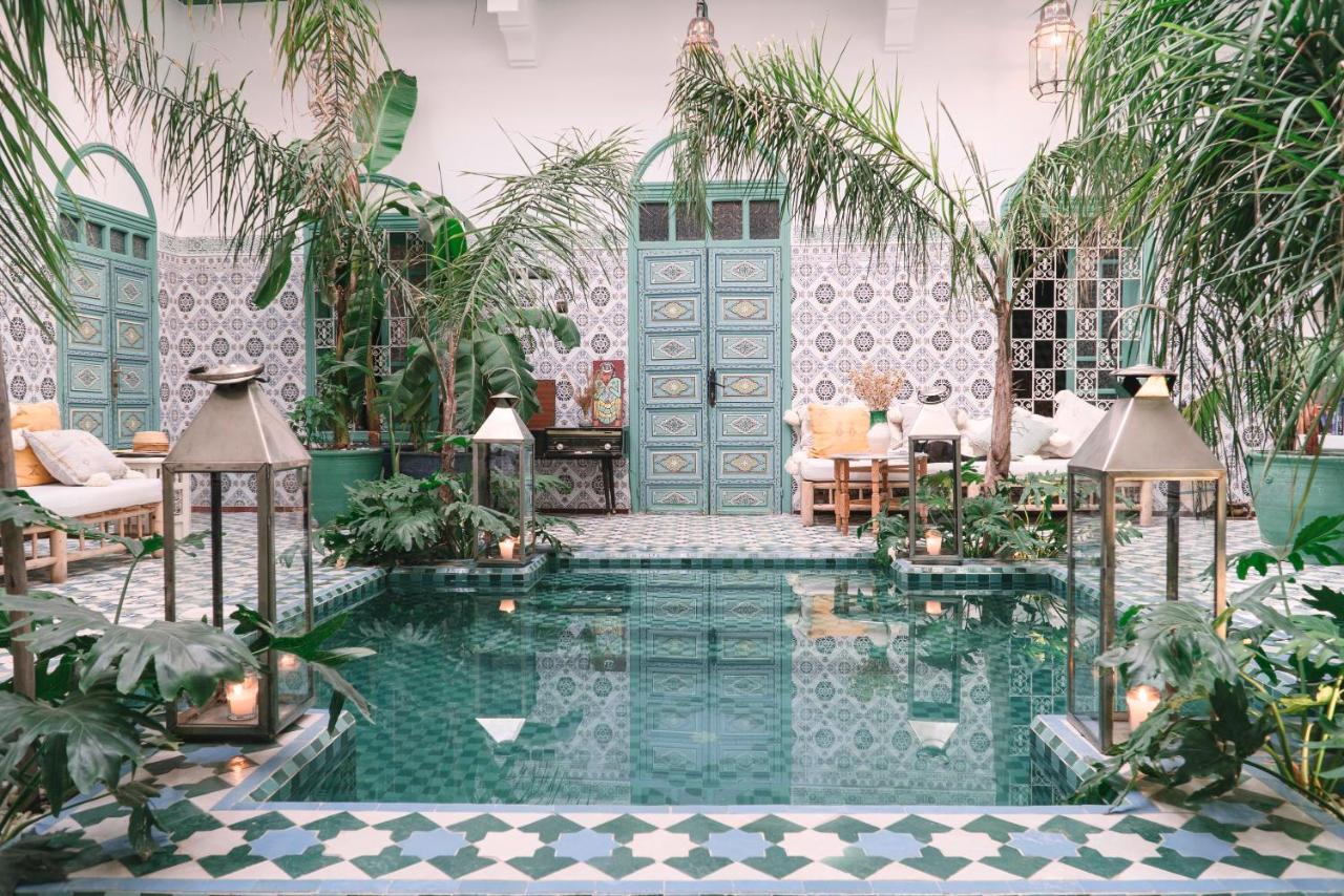 Pool area of Riad BE surrounded with chairs, plush pillows and ornamental plants