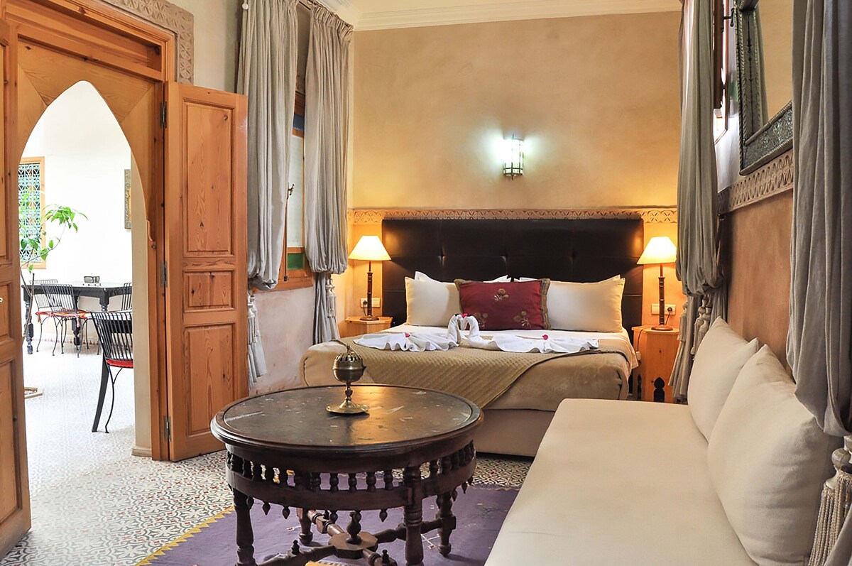 A suite at Riad Inaka with premium bedding, sofa and round table