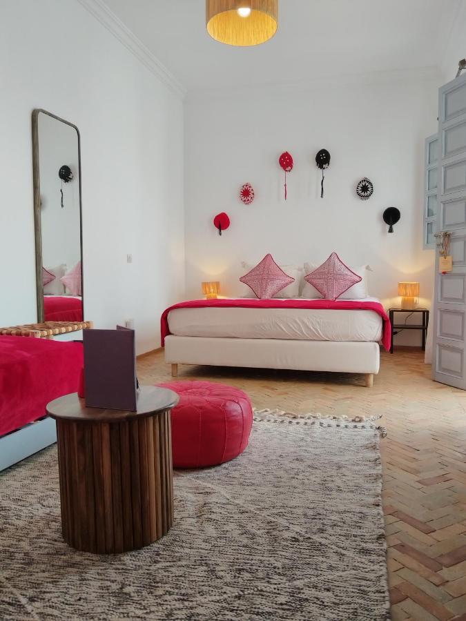 A suite at Riad L'Arganier with white beddings, red pillow cases, sofa and small round table