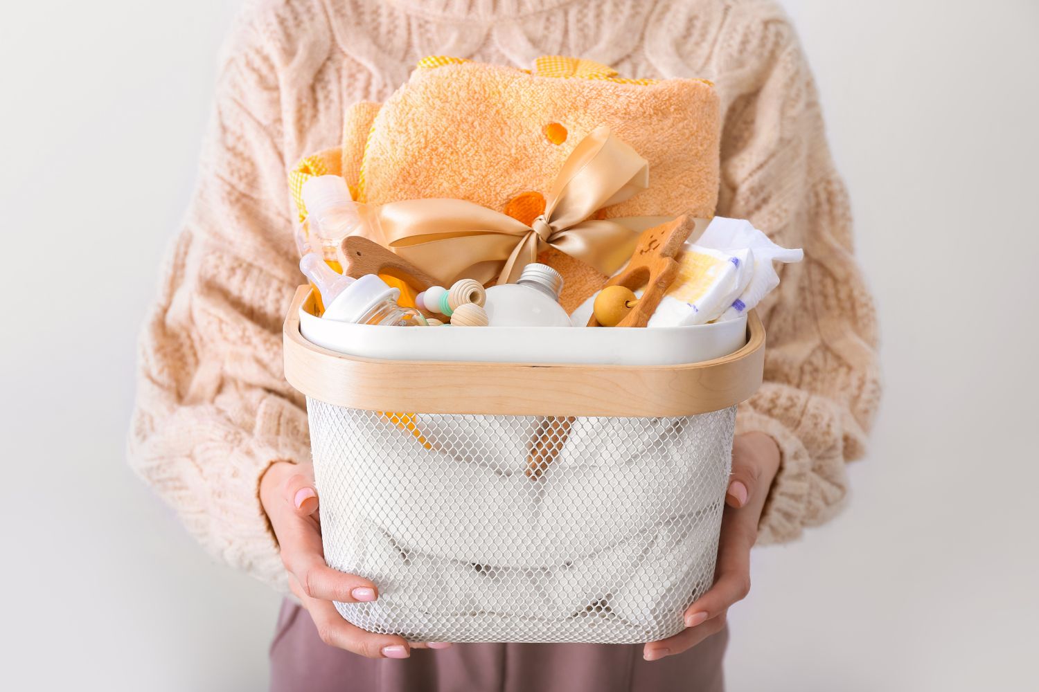 A woman holding a basket of gifts for a baby on white background