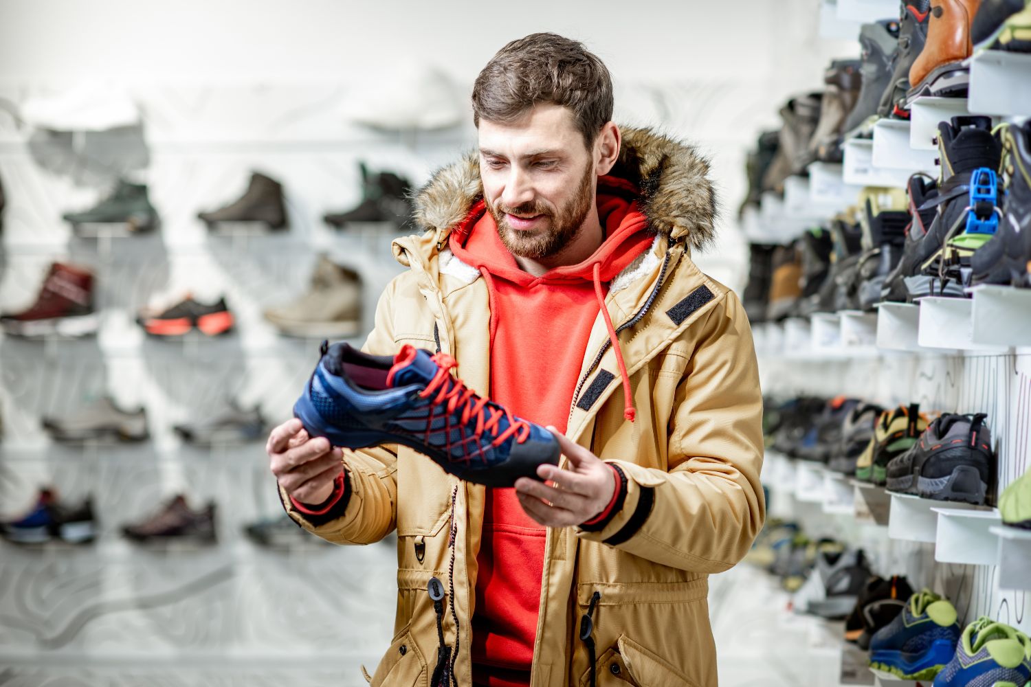 A man in a jacket choosing a hiking shoes in a sports shop