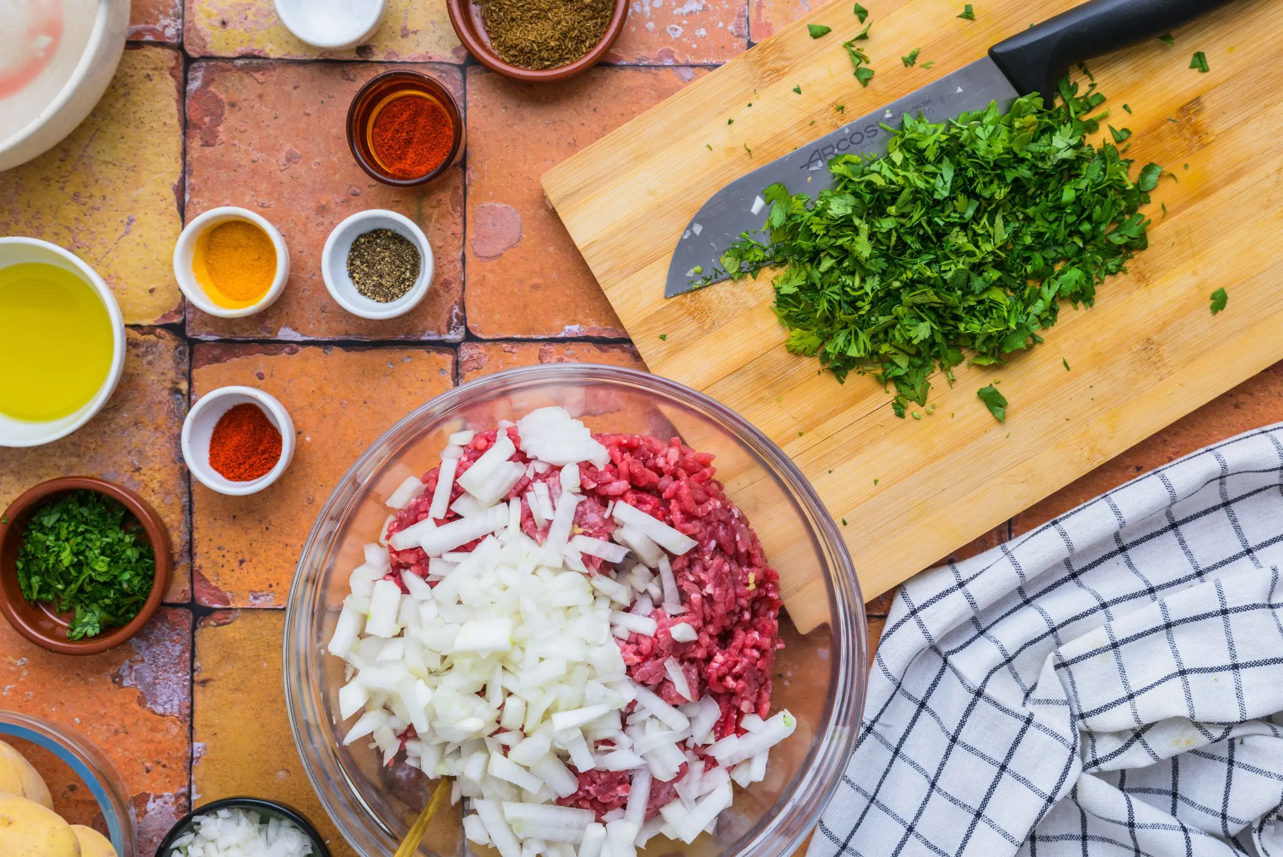 Mixing seasoning and meat in making Moroccan kefta and potatoes