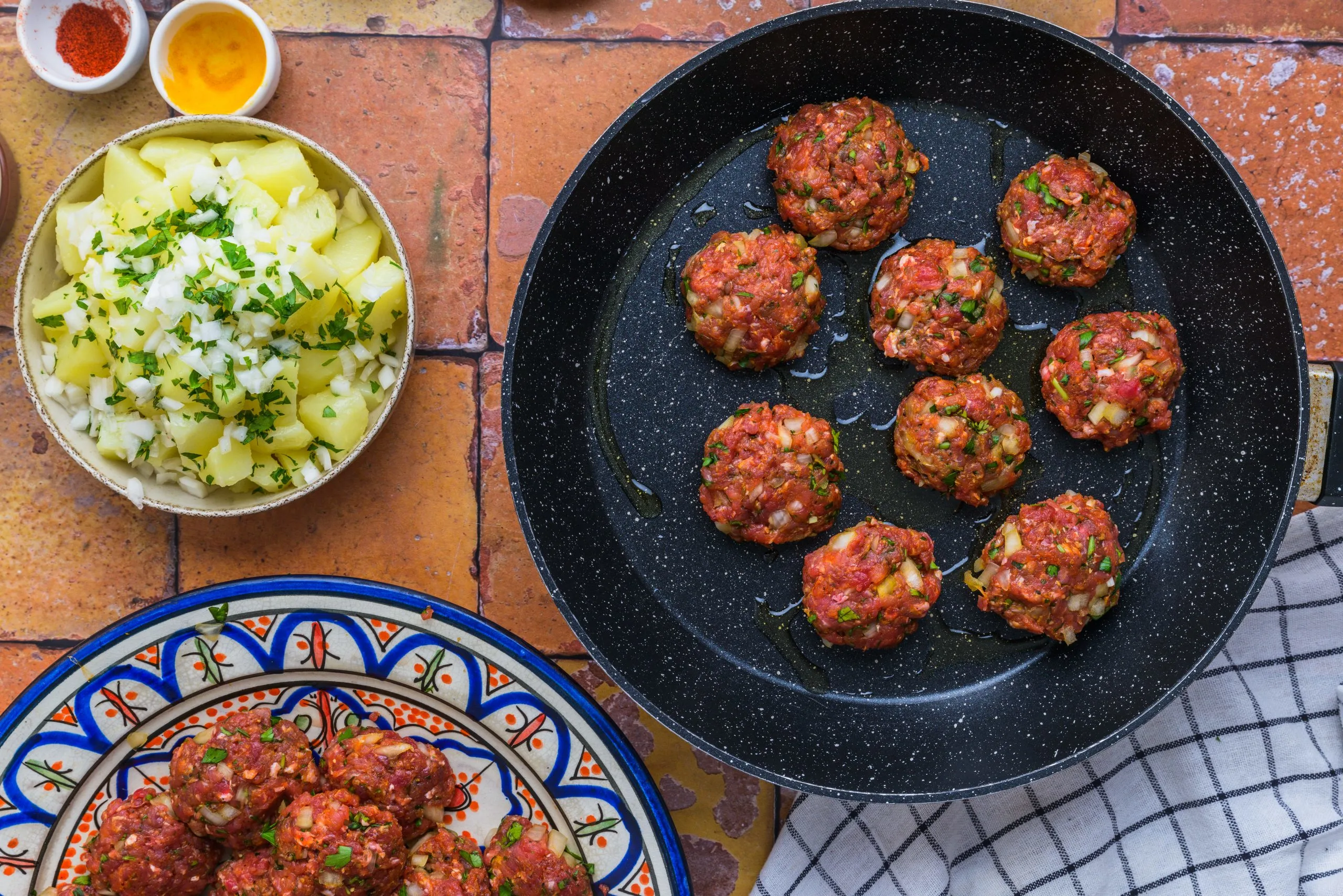 Moroccan kefta and potatoes cooking in a pan