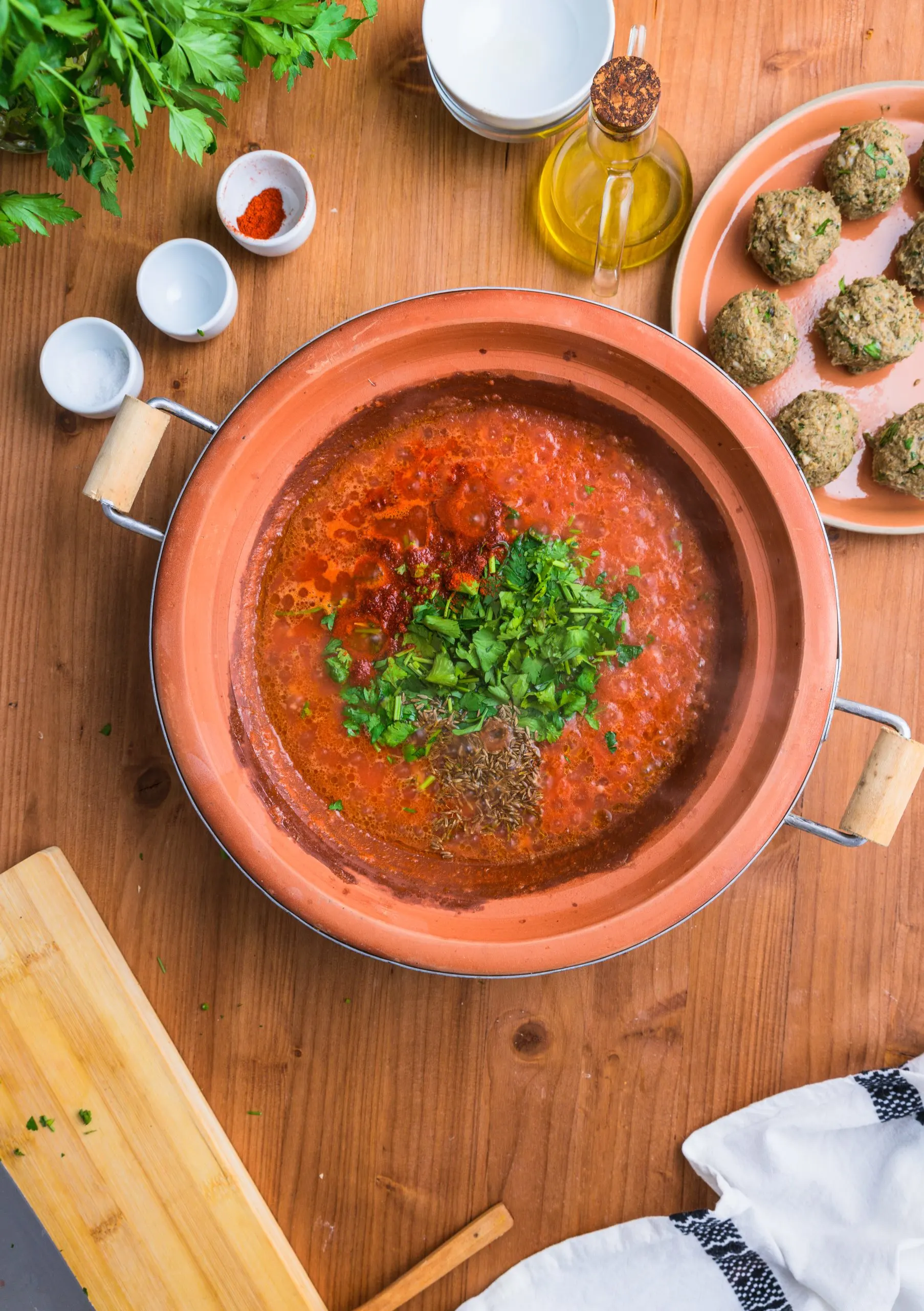 Adding herbs and spices to the Moroccan sardine meatballs tagine dish