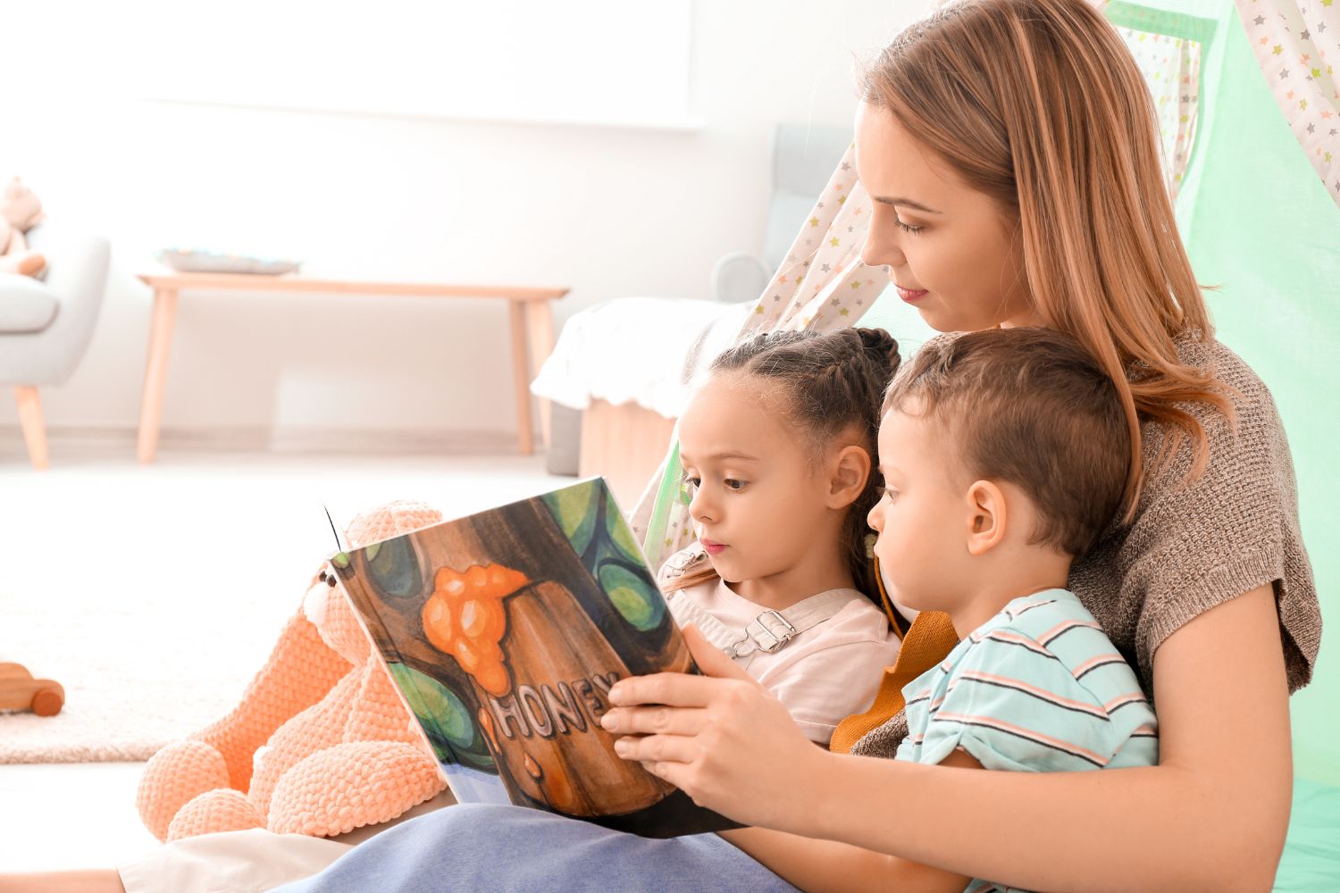 Woman and little children reading book at home