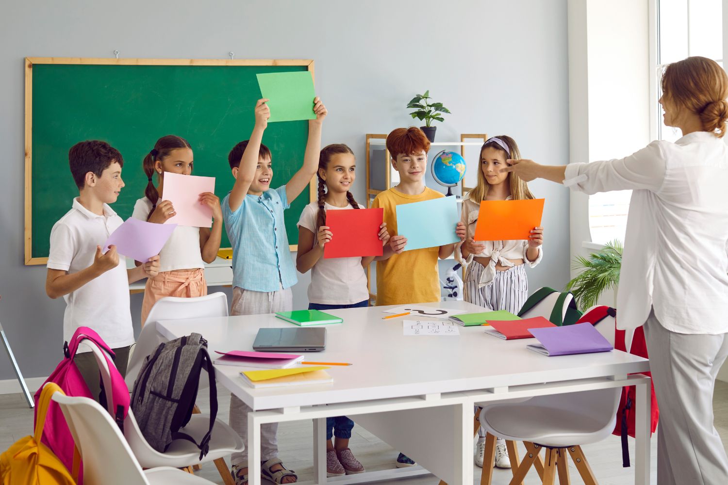 Children holding colored paper sheets together at school 