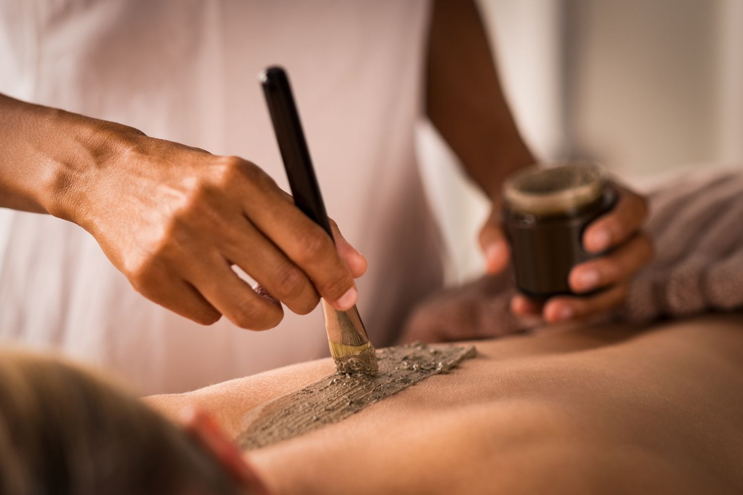 Beautician applying henna paste on a woman's body