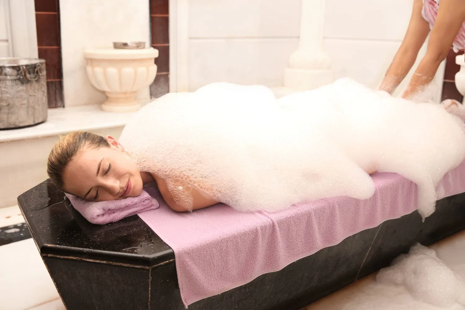 Young woman covered with foam in Hammam