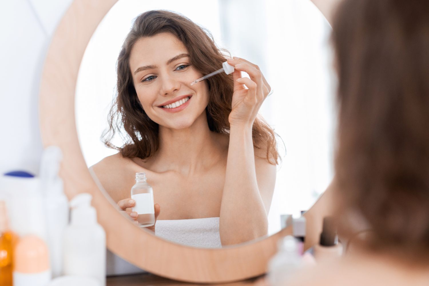 Cheerful girl using argan oil for hydrating skin during summer