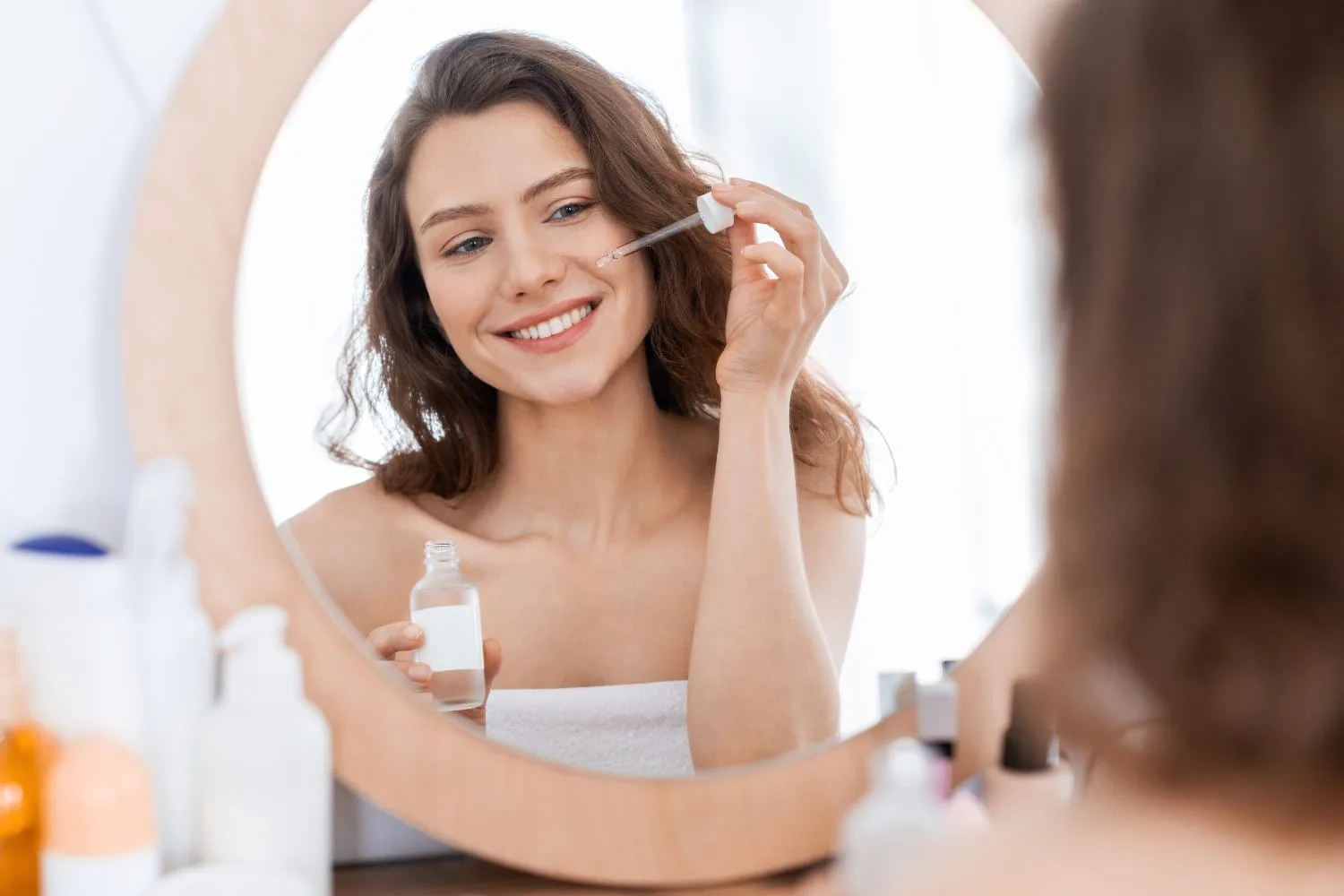 Cheerful girl using argan oil for hydrating skin during summer